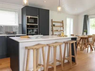 a kitchen with black cabinets and a counter with stools at Blackthorn Copse in Ulverston