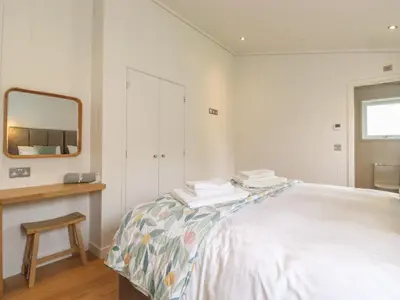 a white bedroom with a bed and a mirror at Blackthorn Copse in Ulverston