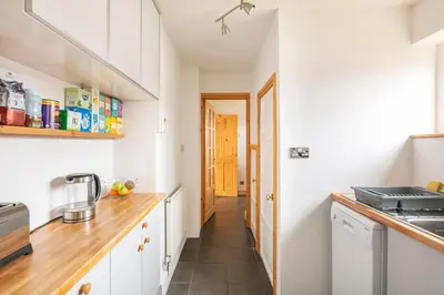 a kitchen with white cabinets and a wooden counter top at Double Room l Large TV l Great Transport Links in Bolton