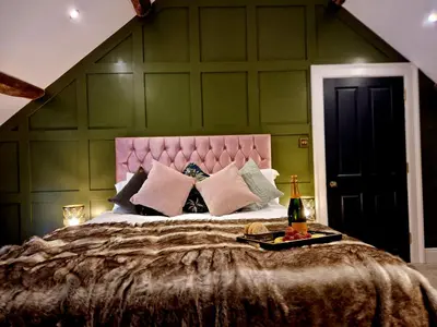 a bedroom with a large bed with a pink headboard at The Cruck in Preston