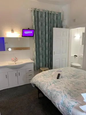 a bedroom with a bed and a sink and a mirror at The Danescourt in Blackpool