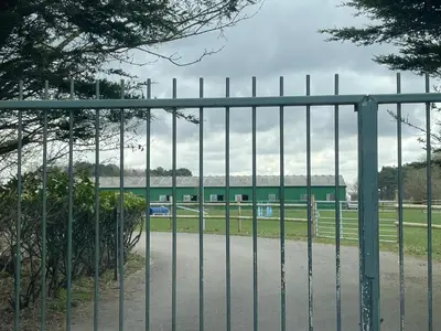 a gate in front of a field with a building at Formby Point in Liverpool