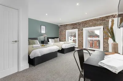 a bedroom with two beds and a brick wall at Host Liverpool - The Wavertree Rooms in Liverpool