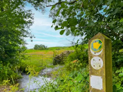 a sign in the middle of a path at The Stable, Broughton Beck, a ground floor cottage close to a beach and Windermere in Spark Bridge