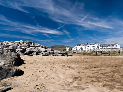 a beach with rocks and a building in the background at Apartment 1 West County by Prestige Properties SA in Millom
