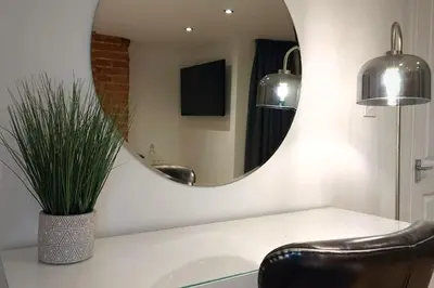 a bathroom with a mirror and a chair and a sink at 2 Bedroom City Centre Duplex Apt in Preston