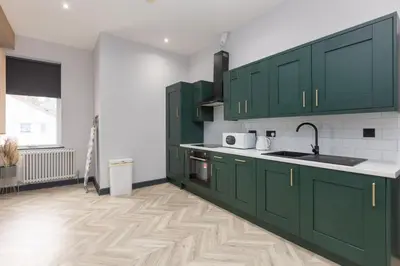 a kitchen with green cabinets and a wooden floor at GiGi's in Blackpool