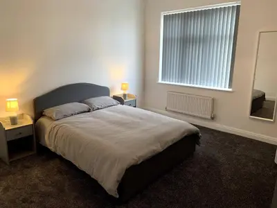 a bedroom with a large bed with two tables and a window at New large 2 bedroom apartment with private parking in Lea Town