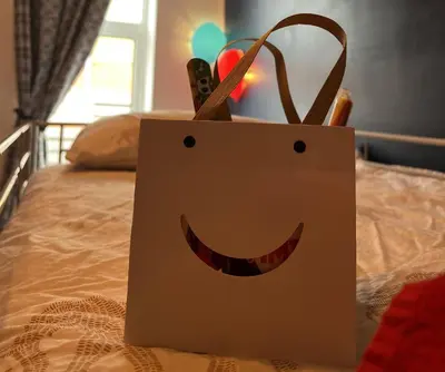 a shopping bag with a smiley face on a bed at Winter Gardens Large Flat 1 in Blackpool
