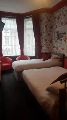 a hotel room with three beds and a window at Valdene Hotel in Blackpool