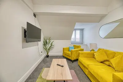 a living room with a yellow couch and a table at Fairhaven View by Guestz in Lytham St Annes
