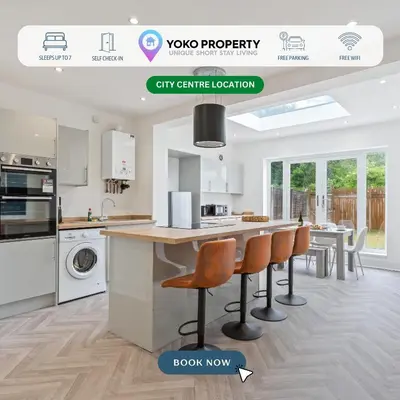 a kitchen with white cabinets and a kitchen island with chairs at Beautiful House - Sleeps up to 7 - Free Parking, Fast Wifi and Smart TV by Yoko Property in Wigan