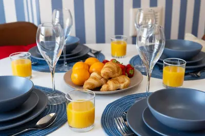 a table with plates of food and glasses of orange juice at Comfy 5 star Stays - 6 Bedrooms - Sleeps 8 - Free Parking & WiFi - Wirral in New Brighton