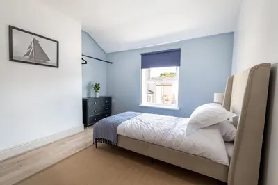 a bedroom with blue walls and a bed with a window at Red & Blue flat 15mins to Liverpool city centre, free parking in New Brighton