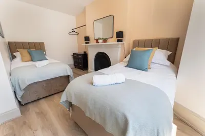 a bedroom with two beds and a mirror on the wall at Terracotta Apartment, free WiFi & parking, coastal location in New Brighton