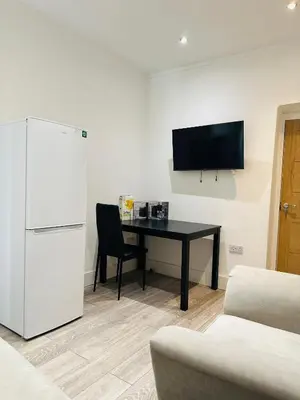 a living room with a table and a refrigerator at Luxury rooms Liverpool in Seacombe