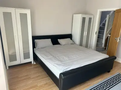 a bed with a black frame in a room at Entire Seaside Home 6 Private BedRooms Sleeps 10,4 Minute Walk To Station in New Brighton