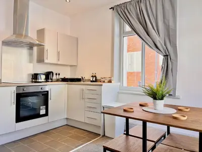 a kitchen with white cabinets and a wooden table at Apartment 6 in Blackpool