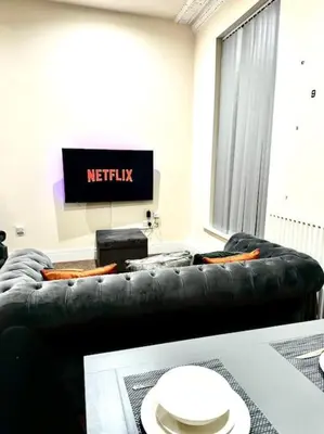 a living room with a black couch and a television at City Centre 2 Bed 2 Bath Apartment in Preston