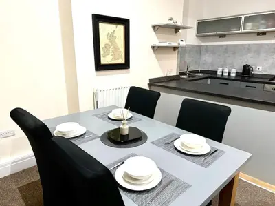 a dining room table with black chairs and a kitchen at Luxury City Apartment 2 Bedroom Suite in Preston