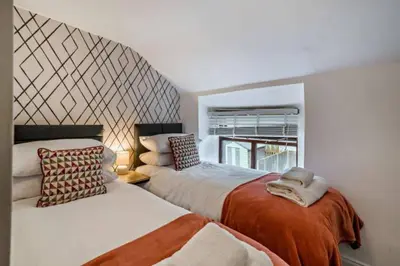 a bedroom with two beds and a window at Quarter Deck in Ulverston