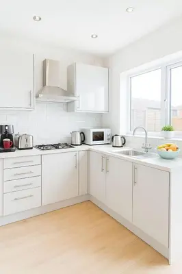 a white kitchen with white cabinets and a sink at Prime Comfort Wigan in Ince-in-Makerfield