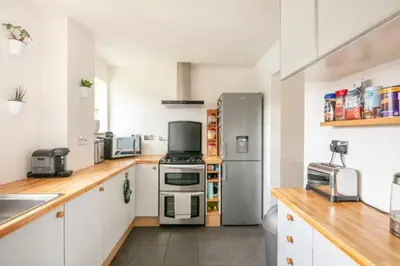 a kitchen with a stainless steel refrigerator and white cabinets at Bright Double Room, Smart TV, Very Close to Train Station in Egerton