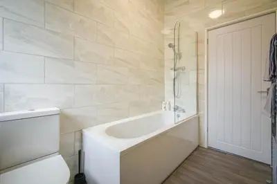 a white bathroom with a tub and a toilet at Modern House Blackburn in Blackburn