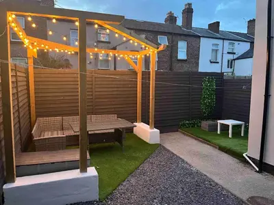a patio with a bench under a pergola with lights at Flat1 Large modern King Bed flat, private bedroom Ryan's place in Walton on the Hill