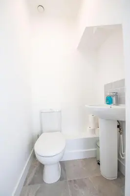 a white bathroom with a toilet and a sink at Modern 3-Bed Home-Liverpool Stay in Sefton