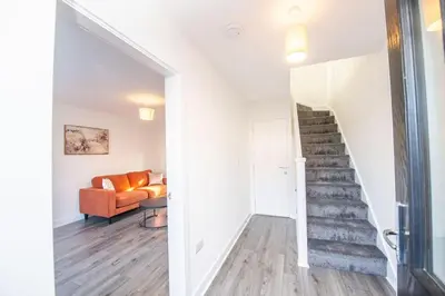 a staircase in a living room with a orange couch at Stylish 3-Bed Home-Liverpool in Liverpool