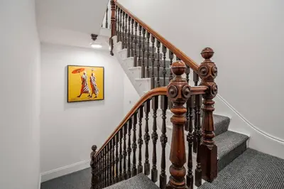 a staircase with a wooden rail and a painting on the wall at Cosy Nook Kitchen w Washer & SofaBed Parking in Liverpool
