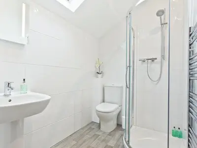 a white bathroom with a shower and a toilet at Pier Cottage in Arnside