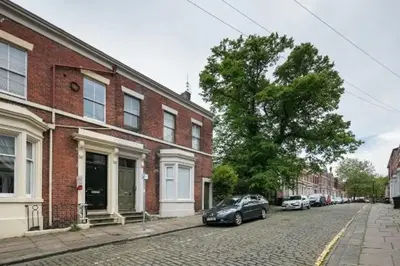a black car parked on a street next to a brick building at Stylish City Centre Apartment With Parking in Preston