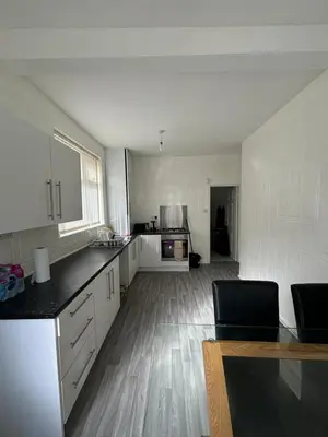 a large kitchen with white cabinets and a wooden floor at Cozy Double Room with 5 Minute Walk to Anfield Stadium ideal for Matchdays in Liverpool