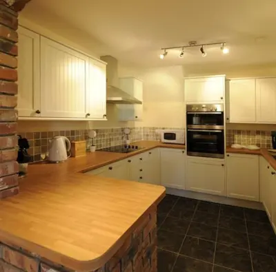 a kitchen with white cabinets and a wooden counter top at Marsh Farm Hall in Great Eccleston