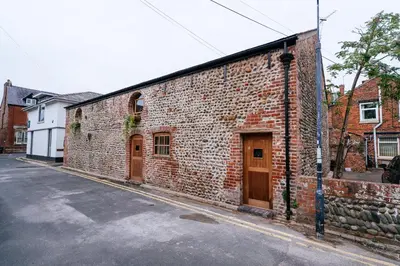 a brick building with wooden doors on a street at The Stables at The Talbot in Lytham St Annes