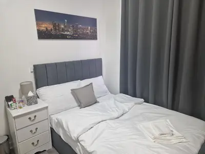 a bedroom with a white bed and a night stand at Sleeps 10- Free Parking- Close To Goodison&Anfield in Liverpool