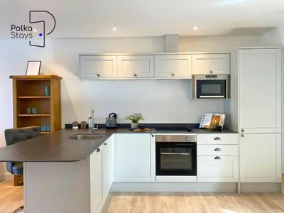 a kitchen with white cabinets and a black counter top at No 6 PolkaStays Ivy Farm Orchard Suite in Plumpton