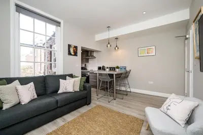 a living room with a couch and a kitchen at Two Apartments in One , City Centre, Sleeps 11! in Liverpool