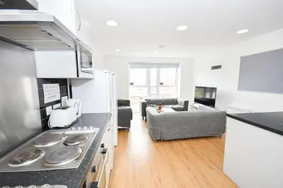 a kitchen and living room with a stove and a couch at Spacious 6 Bedroom Apartment in Liverpool in Liverpool