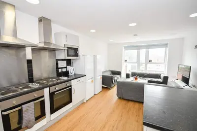 a kitchen and living room with a stove and a couch at Spacious 6 Bedroom Apartment in Liverpool in Liverpool