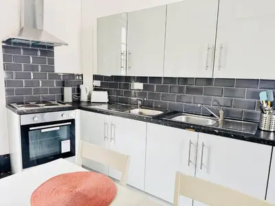 a kitchen with white cabinets and a white table and chairs at Pembroke Place Private Room 1 in Liverpool