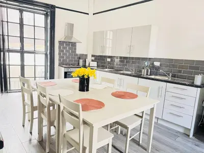 a white kitchen with a white table and chairs at Pembroke Place Private Room 2 in Liverpool
