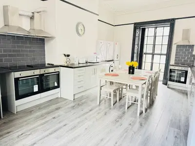 a white kitchen with a table and chairs in it at Pembroke Place Private Room 6 in Liverpool