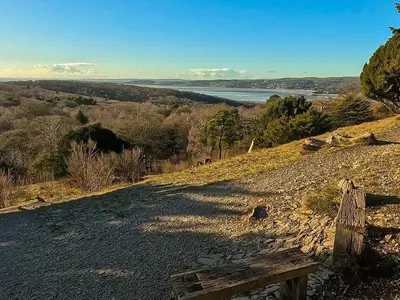 a bench on a hill with a view of the water at Corner Cottage, Yealand Redmayne, ideal family holiday, meet the resident animals in Beetham