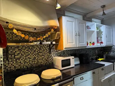a kitchen with white cabinets and a microwave at Grange Cottage in Belmont
