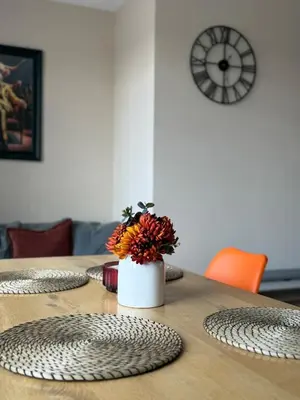 a table with a vase of flowers on top of it at Stylish and Bright 2 Bedroom Flat Free Parking in Wallasey
