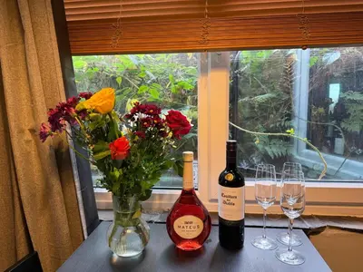 two bottles of wine and glasses on a table with flowers at 4 Bed Retreat-Sleeps 7-Parking-Garden-Lake Views in Bolton