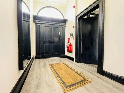 a hallway with black doors and a rug on the floor at Pembroke Place Private Room 2B in Liverpool